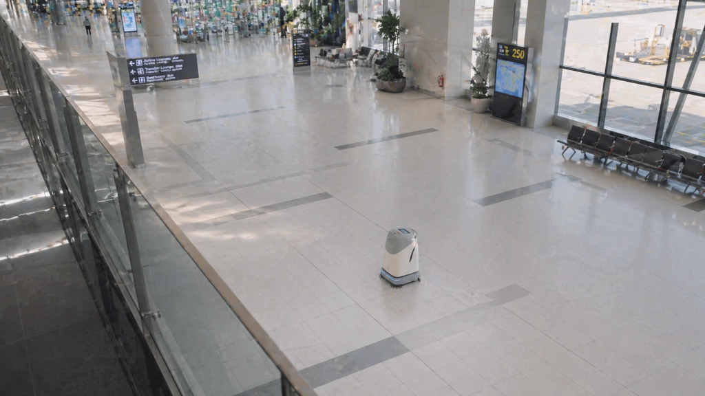 Travellers walking through busy airport terminal walkway with reflective polished floor