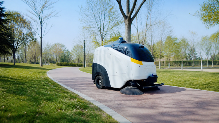 Max 100 autonomous cleaning machine cleaning a paved pathway in a park, helping maintain outdoor public spaces, walkways and council areas.